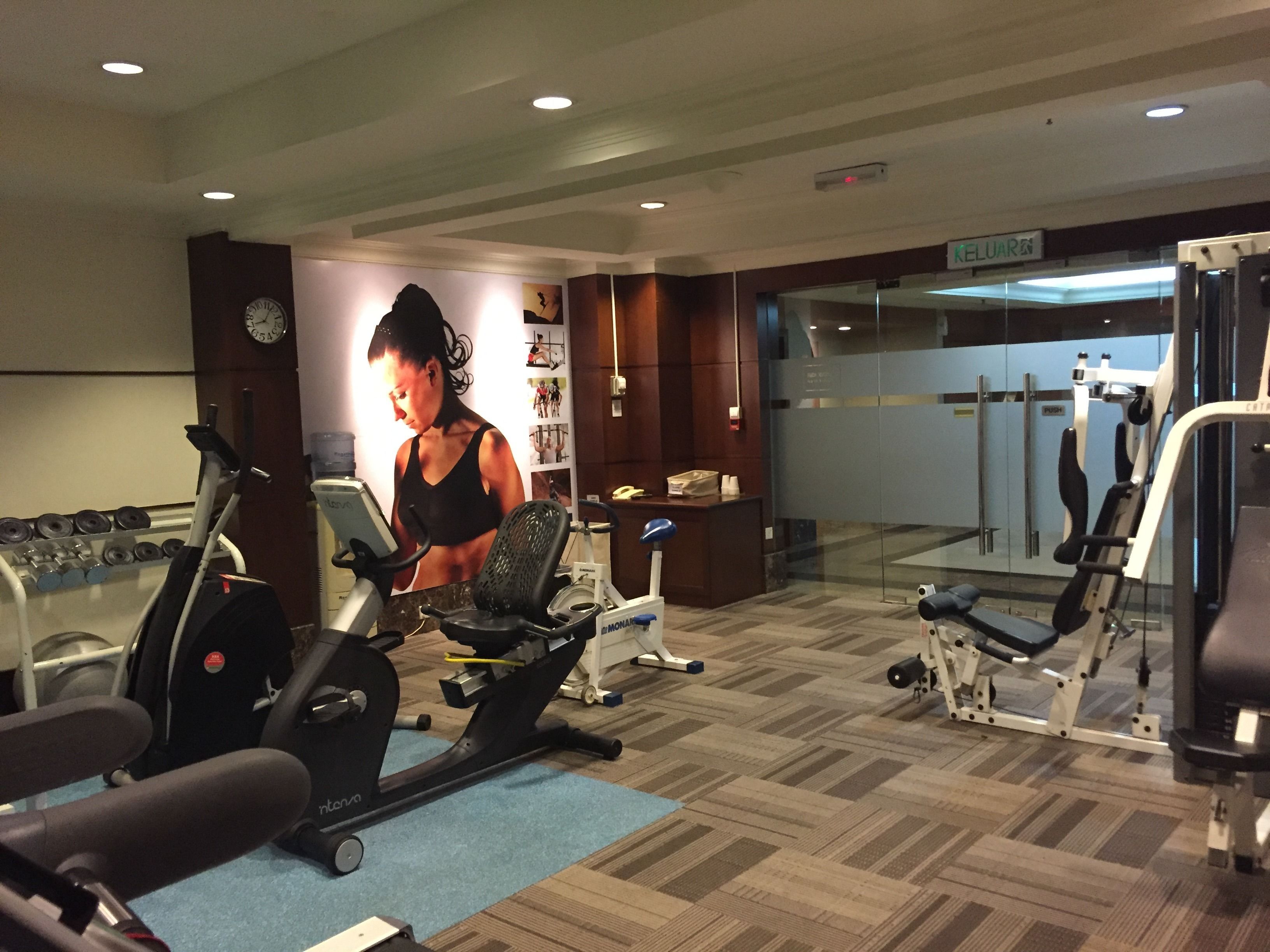 A gym with cardio equipment, weight machines, and a mirror wall.