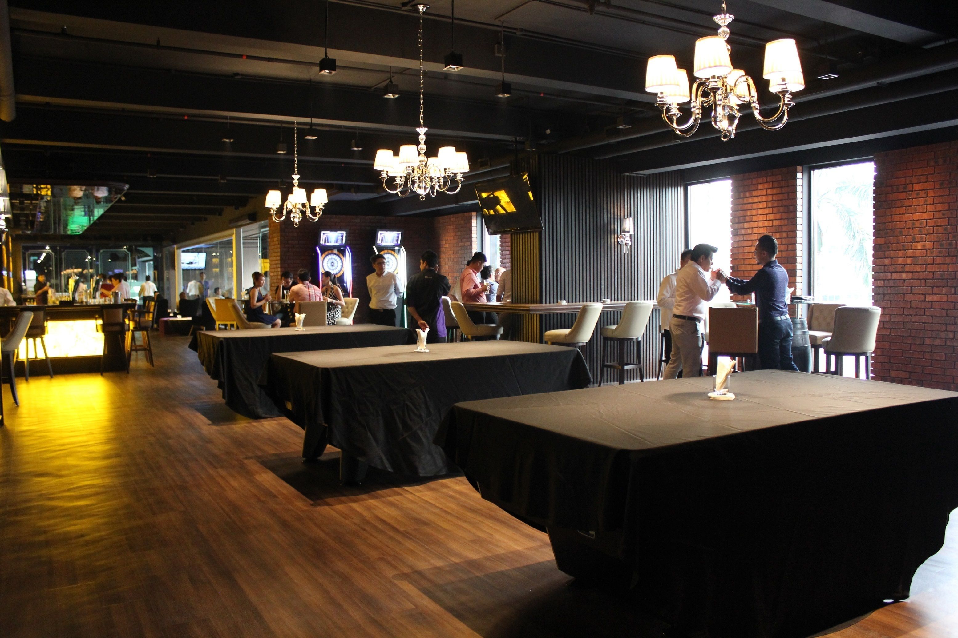 A restaurant with multiple tables, a bar area, and a brick wall.