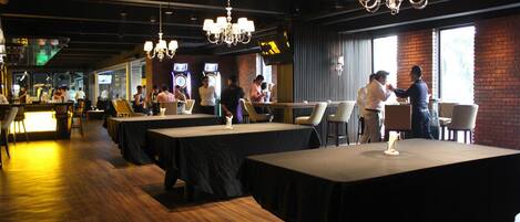 A restaurant with multiple tables, a bar area, and a brick wall.