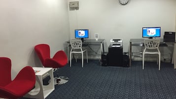 A room with two desks, two chairs, a clock, and a printer.