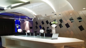 A modern reception desk with a curved design, a laptop, and decorative vases. - Hotel Armada Petaling Jaya (Petaling Jaya)