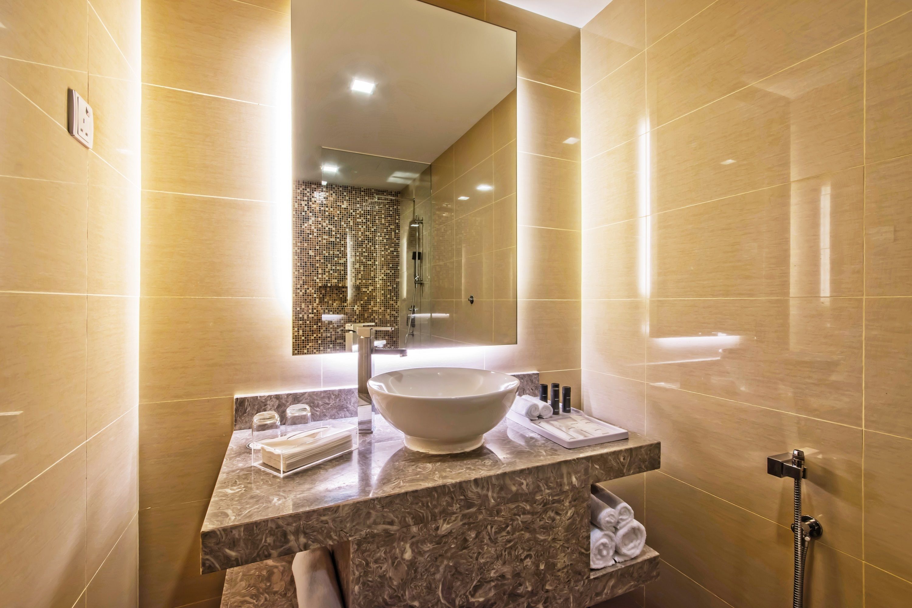 A modern bathroom with a large mirror, a vessel sink, and a handheld showerhead.