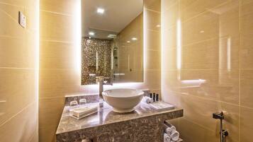 A modern bathroom with a large mirror, a vessel sink, and a handheld showerhead.