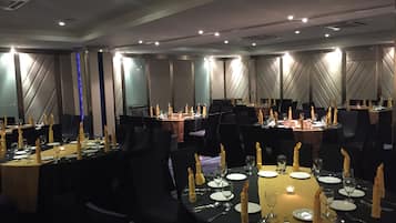 A conference room with round tables, black chairs, and candle centerpieces.