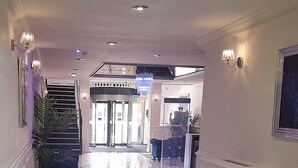 A marble-floored hallway with a reception desk, a staircase, and a door leading to an outdoor area.