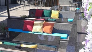 Outdoor seating with colorful cushions and a flower arrangement.