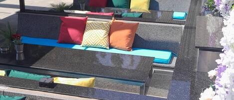 Outdoor seating with colorful cushions and a flower arrangement.