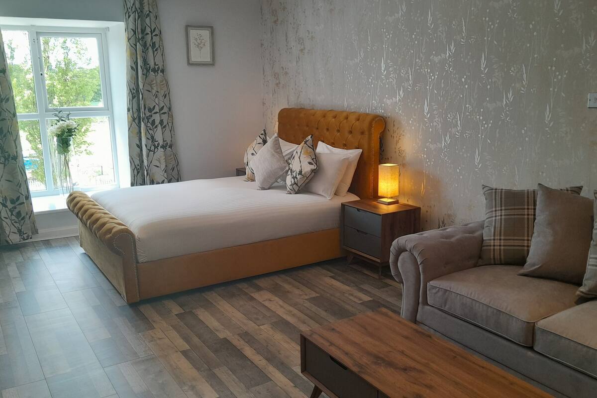A bedroom with a bed, nightstand, and a sofa.