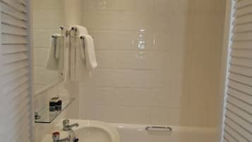 A bathroom with a white sink, a bathtub, and a glass shelf with toiletries.