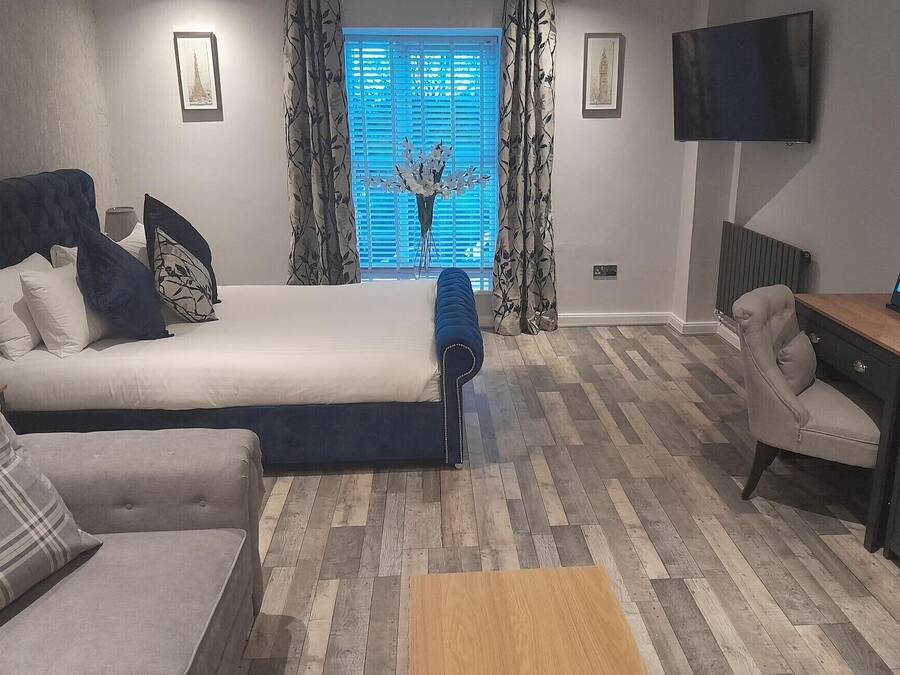 A bedroom with a bed, a sofa, a desk, and a TV.