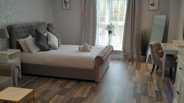 A modern bedroom with a large bed, a desk, and a chair.