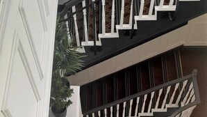 A multi-level interior with white railings, a circular seating area, and potted plants.