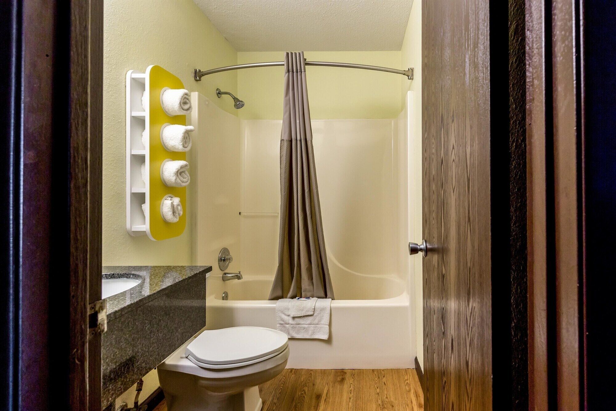 A bathroom with a bathtub, toilet, and a towel rack with towels.