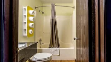 A bathroom with a bathtub, toilet, and a towel rack with towels.