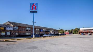A motel with a prominent '6' sign, a parking lot, and a building with a 'two fat guys' sign.