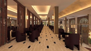 Un hall d’hôtel avec une longue rangée de sièges, un sol à motifs et une grande fenêtre sur le côté droit.