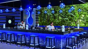 A modern bar area with a counter, stools, and hanging blue spherical lights.