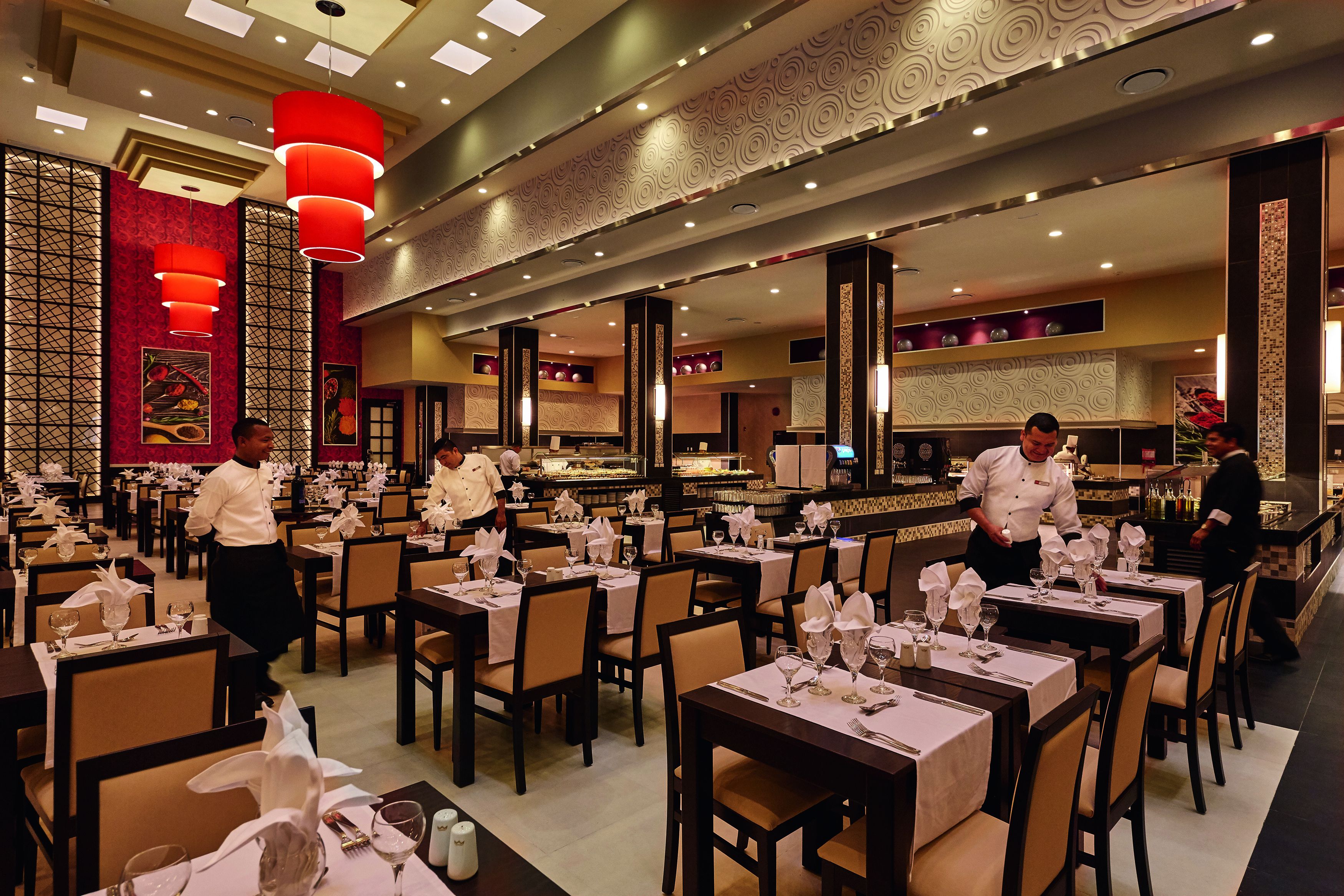 A restaurant with multiple tables set for dining, a bar area, and waitstaff attending to guests.