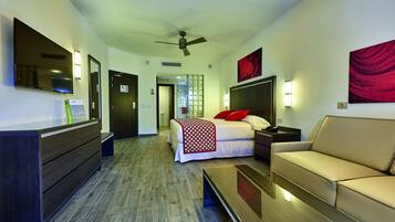 Une chambre d’hôtel équipée d’un lit, d’un canapé, d’un bureau, d’une télévision et d’un ventilateur de plafond.