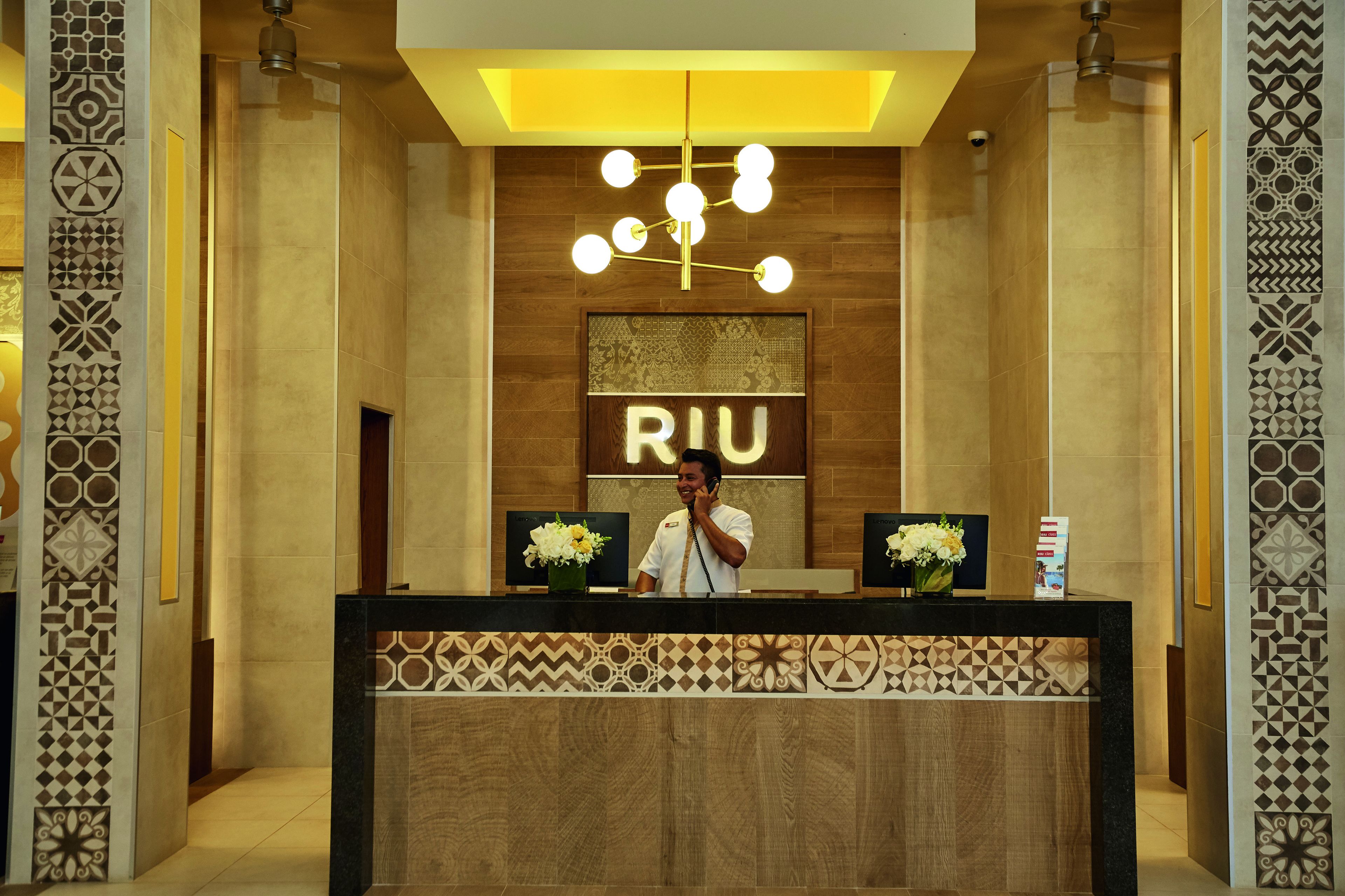 A reception desk with a modern design, featuring a wooden panel and a geometric patterned border.