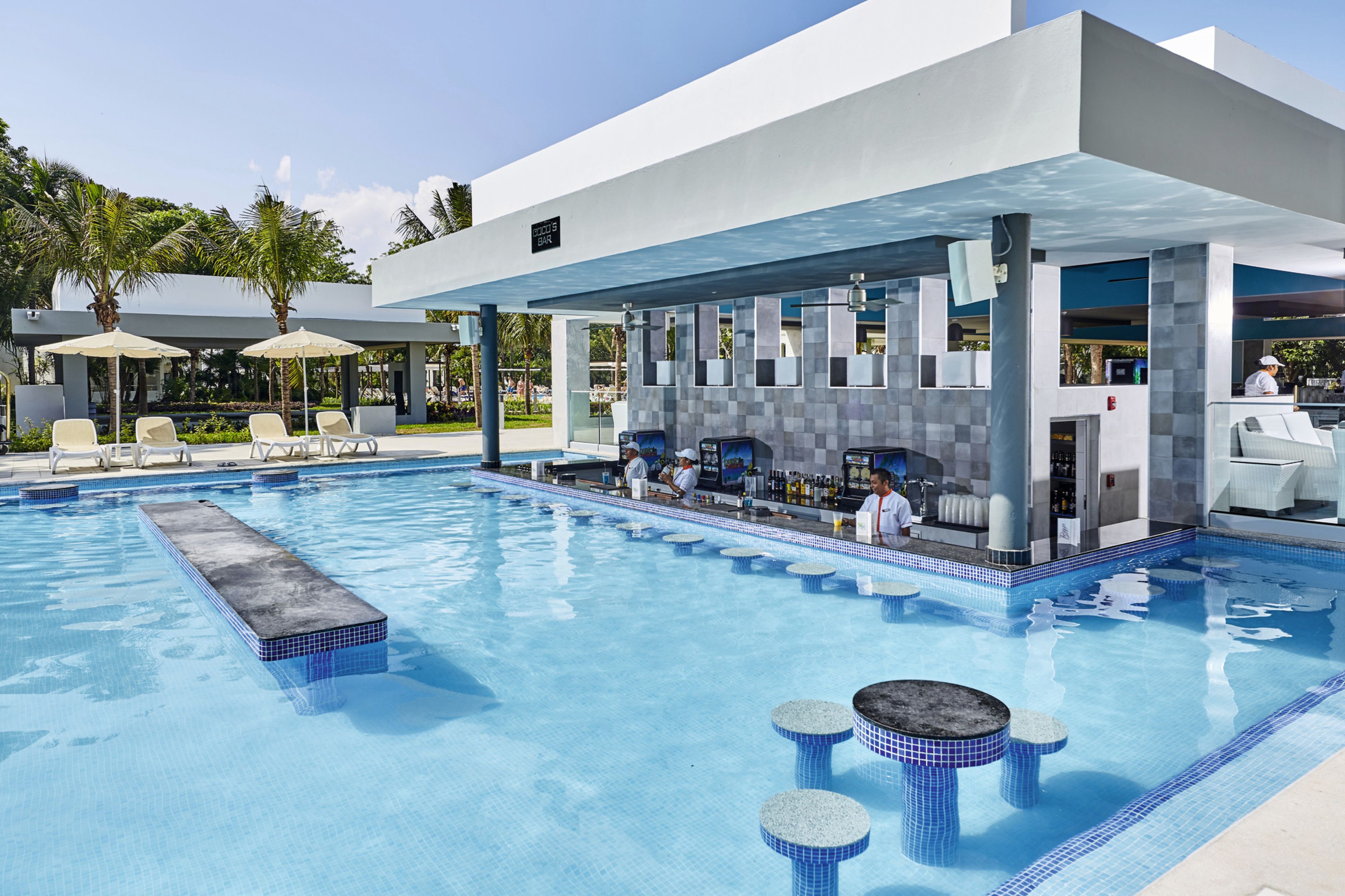 A modern pool area with a bar, lounge chairs, and a covered seating area.