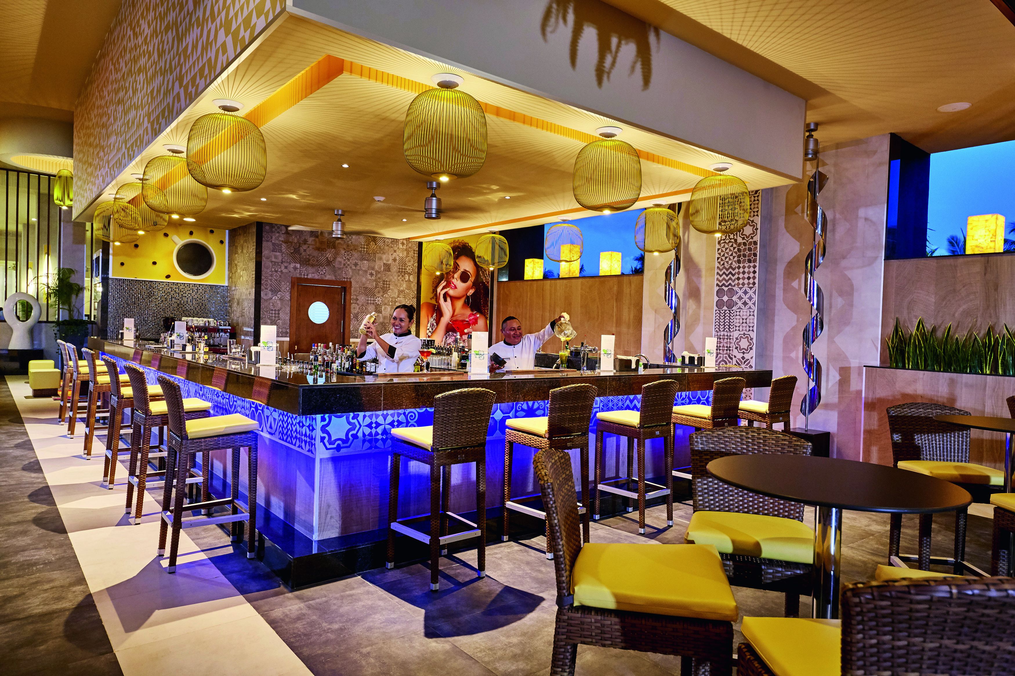 A bar area with a long counter, multiple stools, and a seating area with tables and chairs.