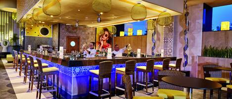 A bar area with a long counter, multiple stools, and a seating area with tables and chairs.