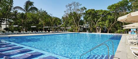 A swimming pool with lounge chairs and a clear blue sky.