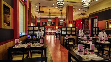 A restaurant with multiple dining tables, chairs, and hanging chandeliers.
