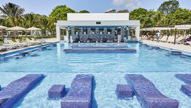 A pool area with lounge chairs and a bar area.