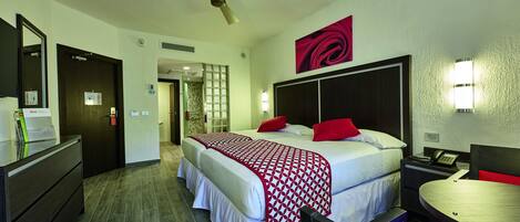 Une chambre d’hôtel équipée d’un lit, d’une table de chevet, d’un bureau, d’une chaise et d’un ventilateur de plafond.