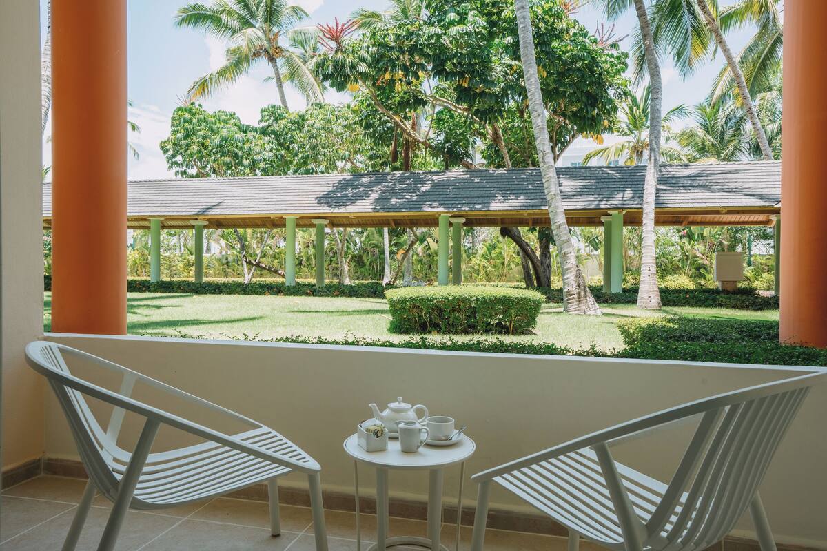 A balcony with two white chairs and a small table with tea set.