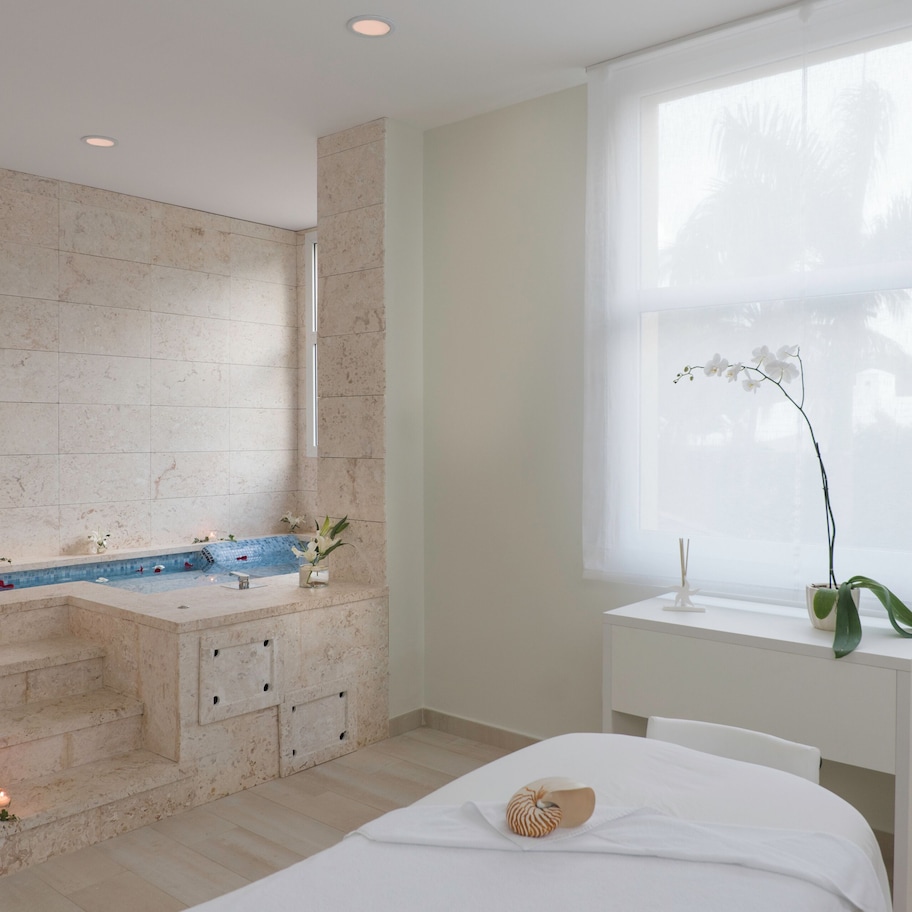 A modern bathroom with a bathtub, a sink, and a window with a view of palm trees.