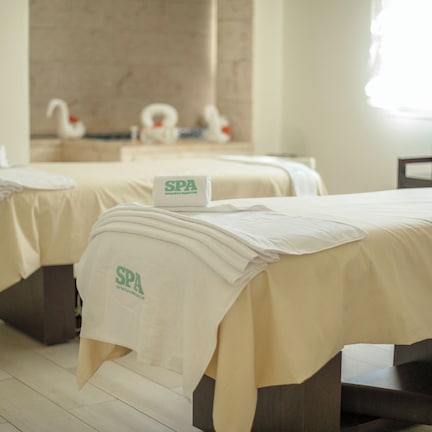 A spa room with two beds, each covered with a white towel and a sign reading "SPA".