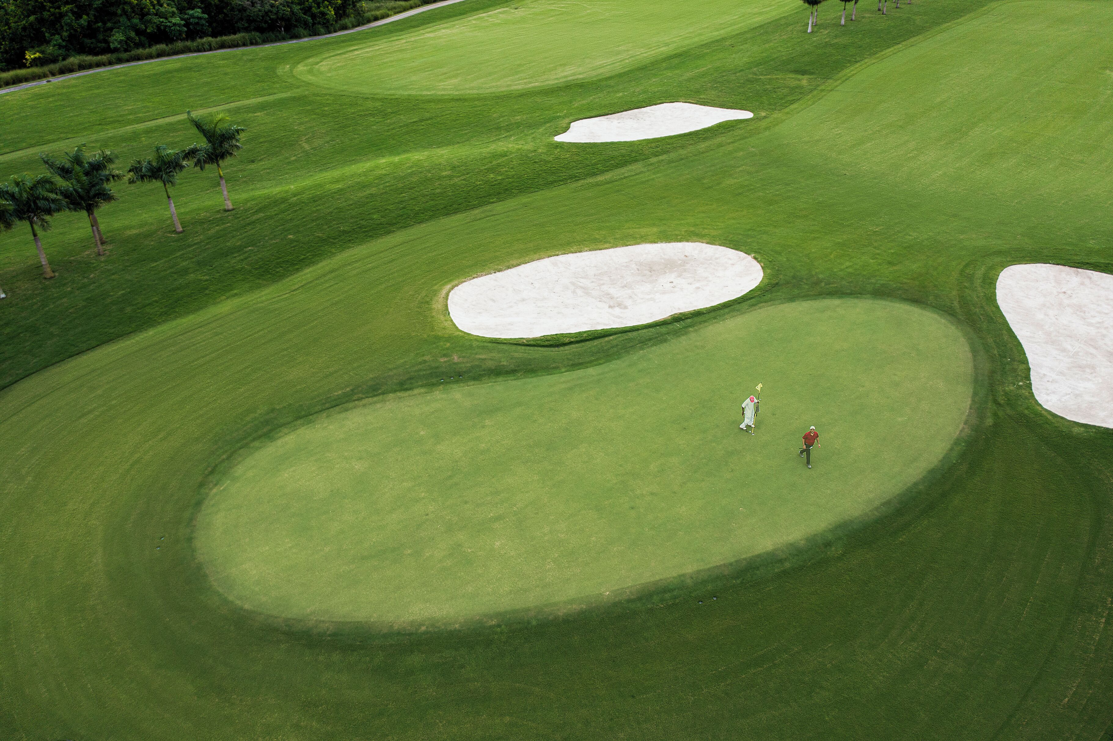 Un campo de golf con búnkeres de arena y palmeras.