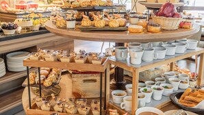 Un buffet proposant une variété de pâtisseries, de desserts et de tasses de café.
