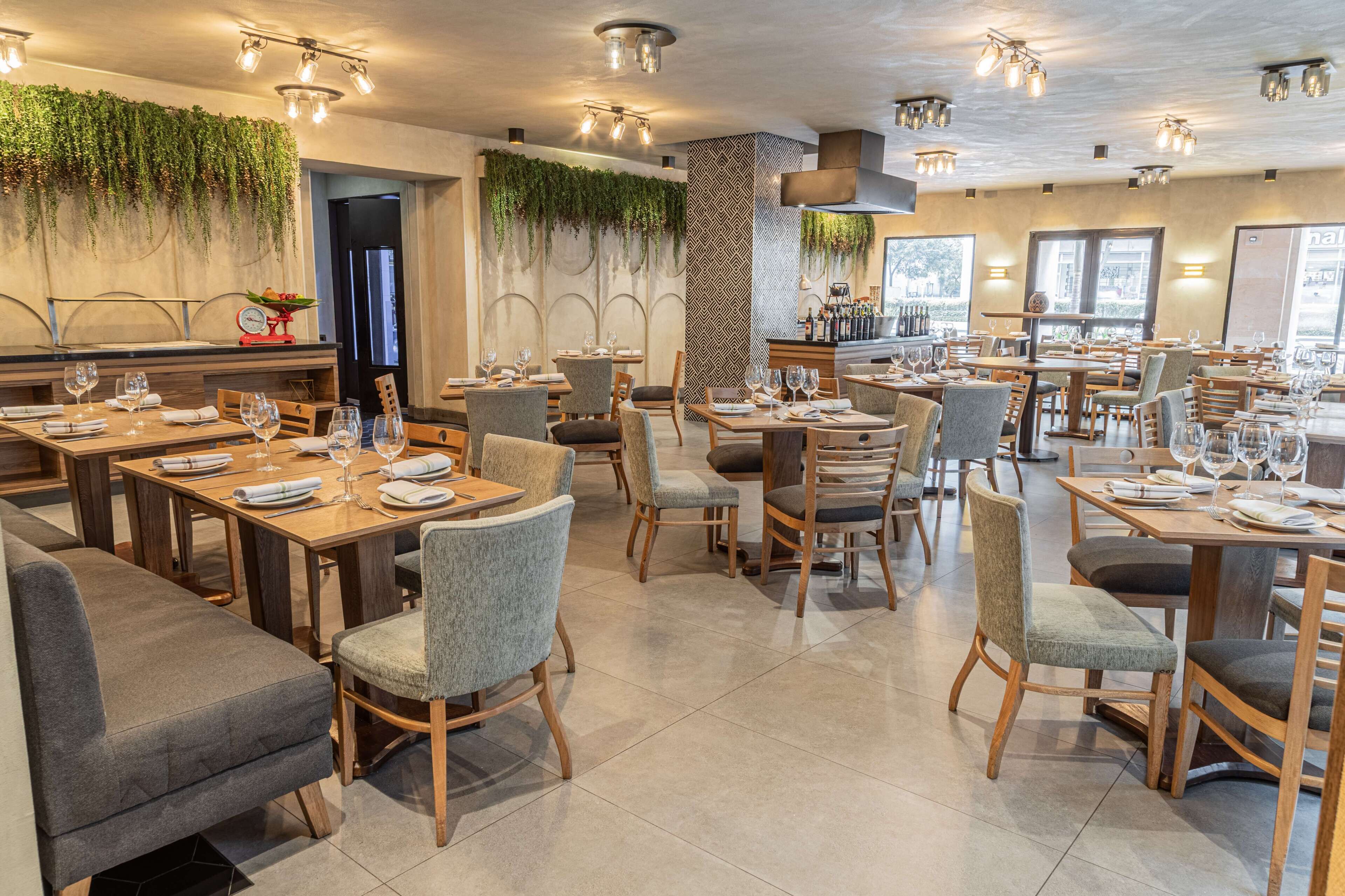 A restaurant with multiple dining tables, chairs, and a bar area.