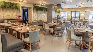 A restaurant with multiple dining tables, chairs, and a bar area.