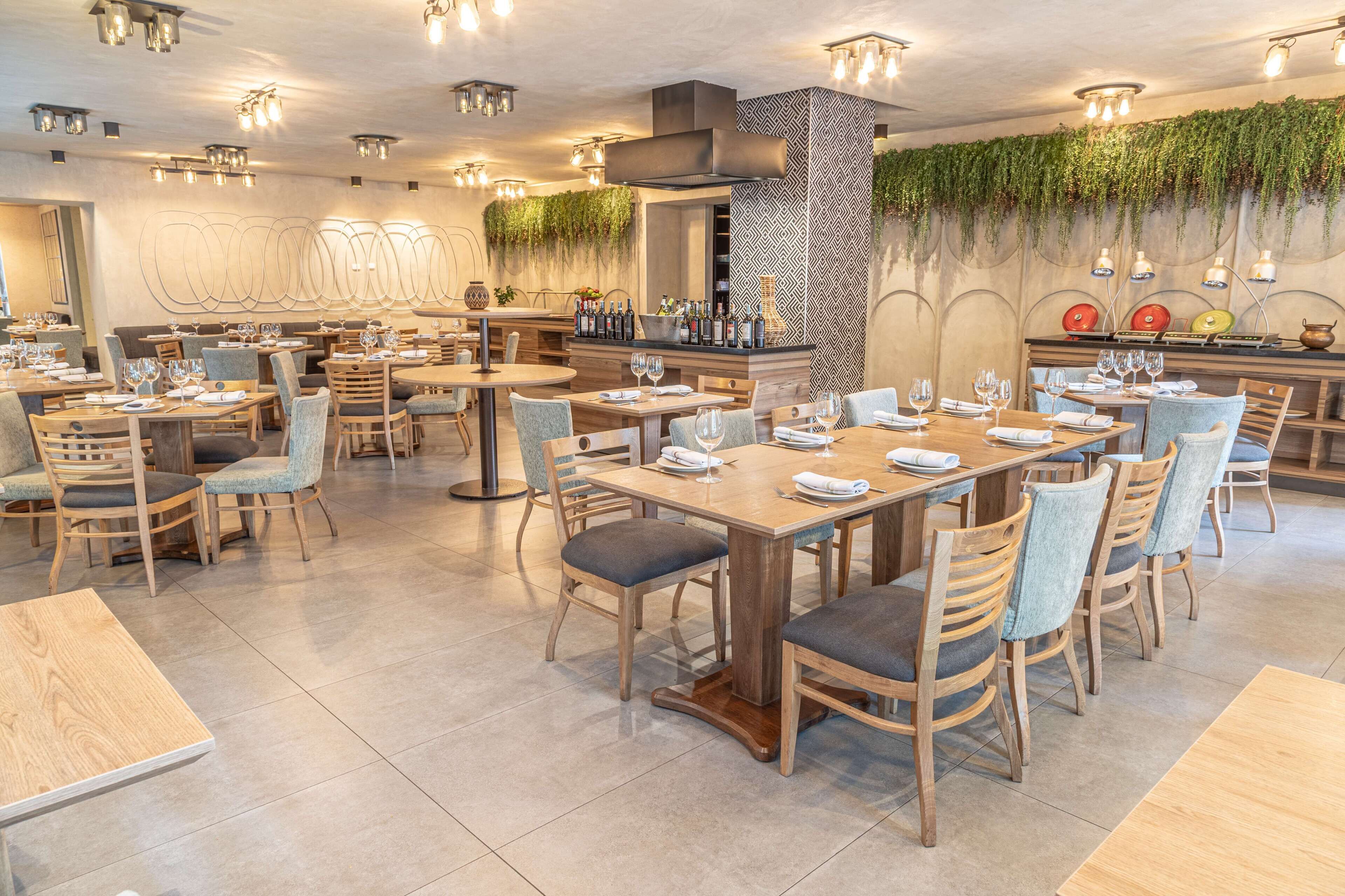 Een restaurant met meerdere eettafels, stoelen en een bar.