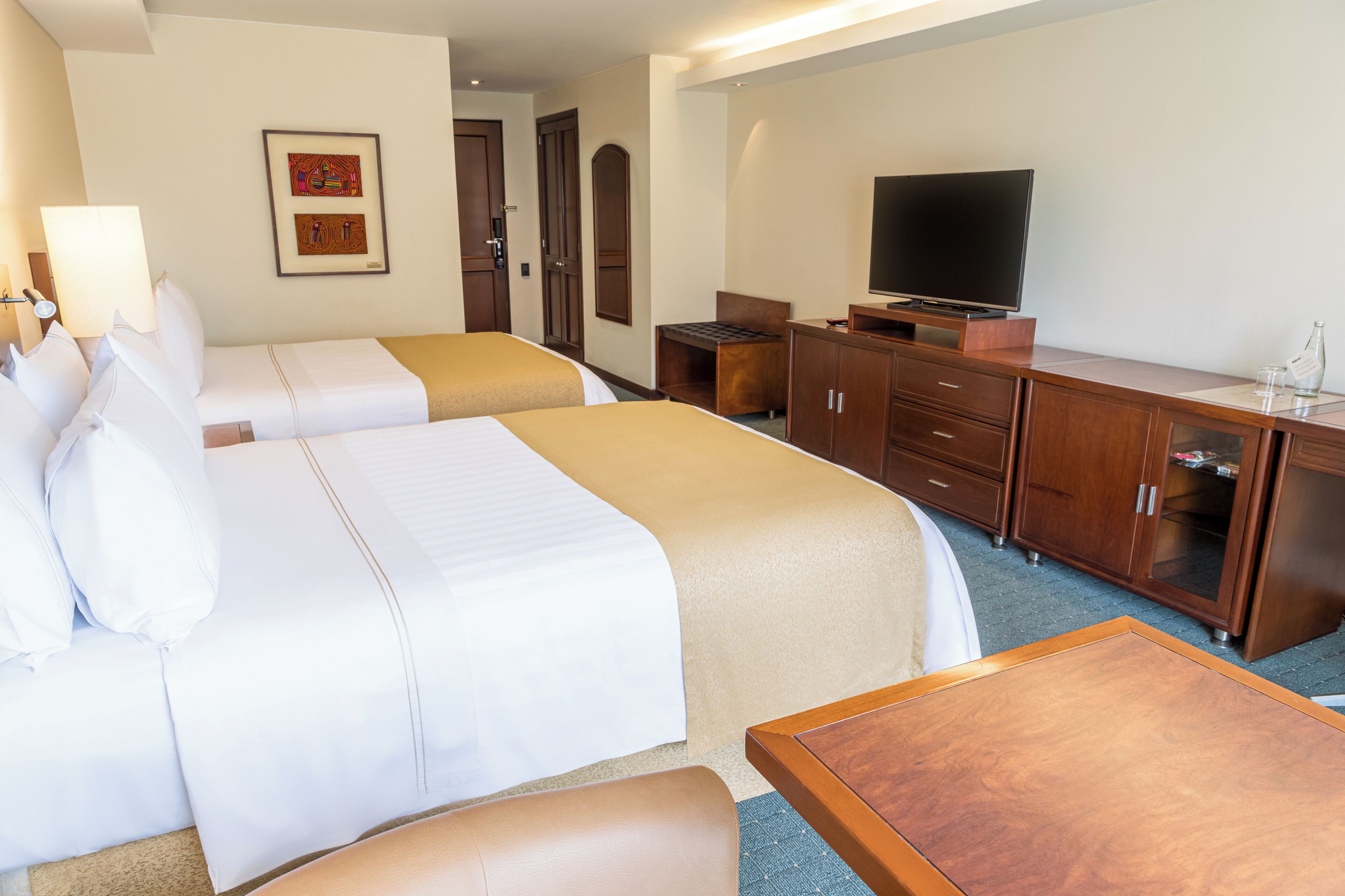 Habitación de hotel con dos camas, televisión, escritorio y armario.