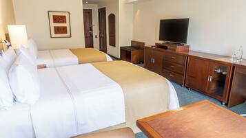 Habitación de hotel con dos camas, televisión, escritorio y armario.