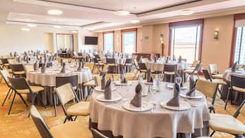 A banquet hall with round tables set for dining, equipped with chairs and table settings.