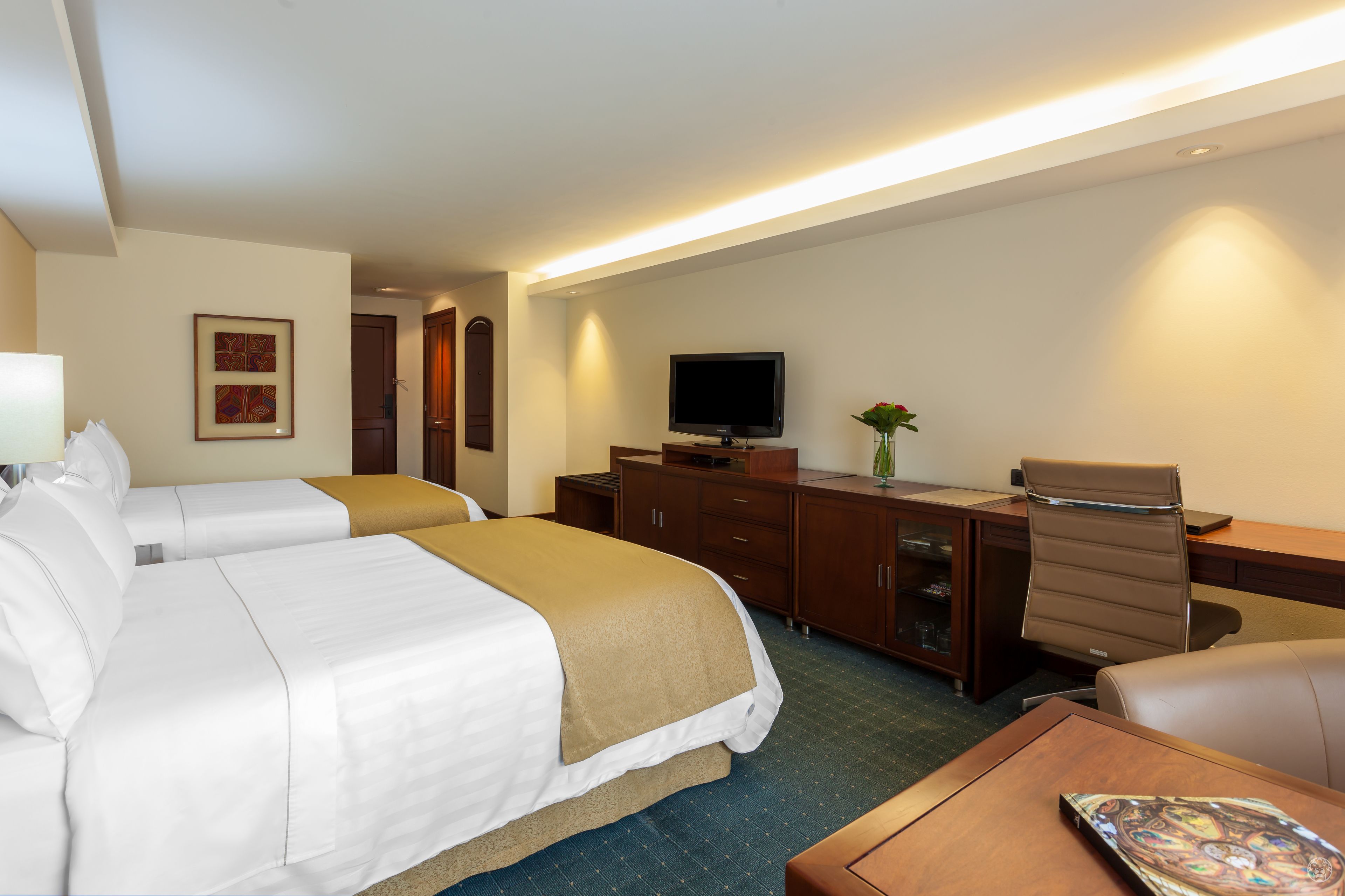 Una habitación de hotel con dos camas, un escritorio, un televisor y una mesita.
