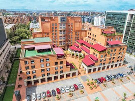 Un hotel a più piani con terrazza panoramica, parcheggio e vista sulla città.