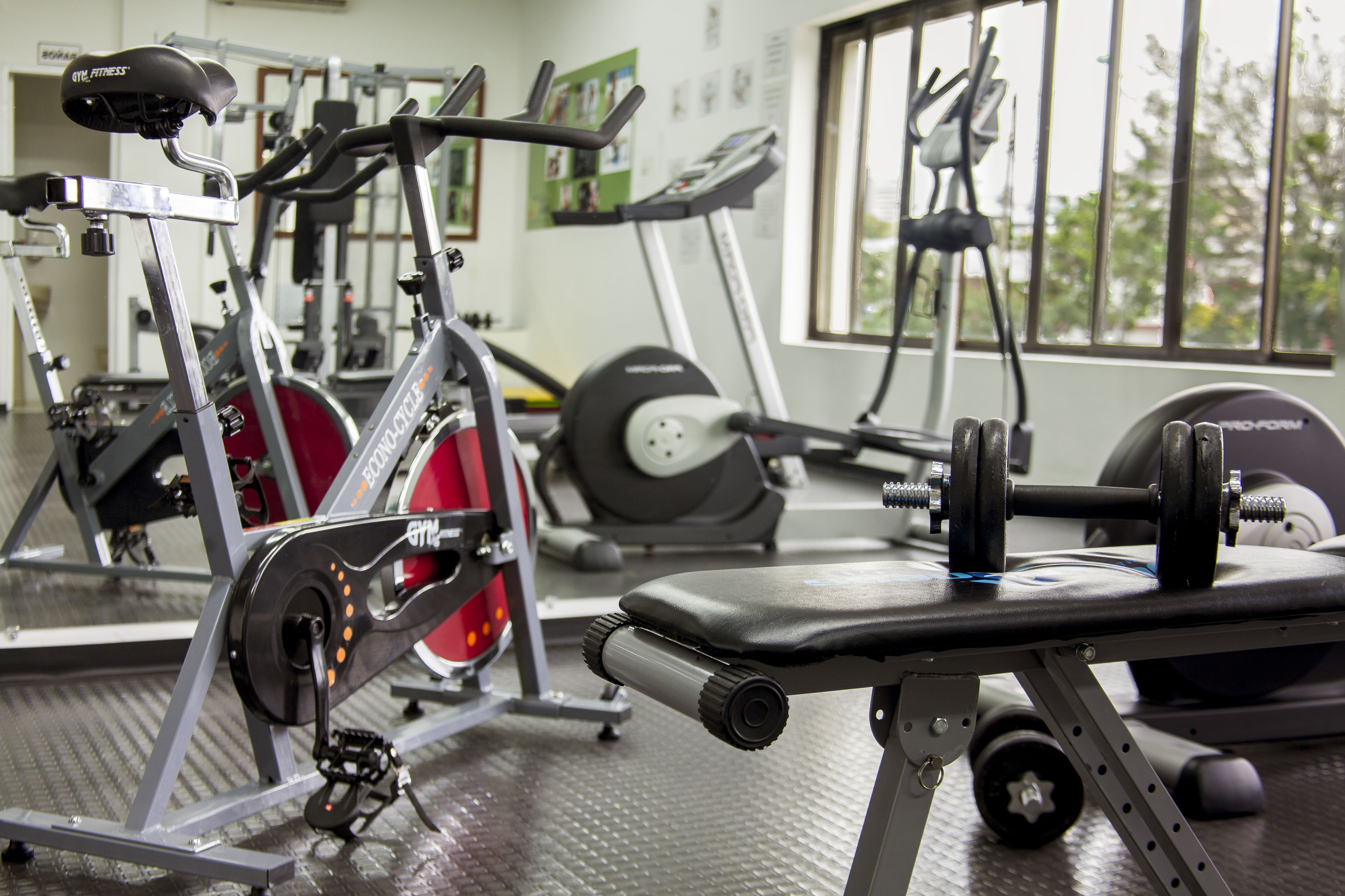 A gym with various exercise equipment, including a treadmill, stationary bike, and weight bench.