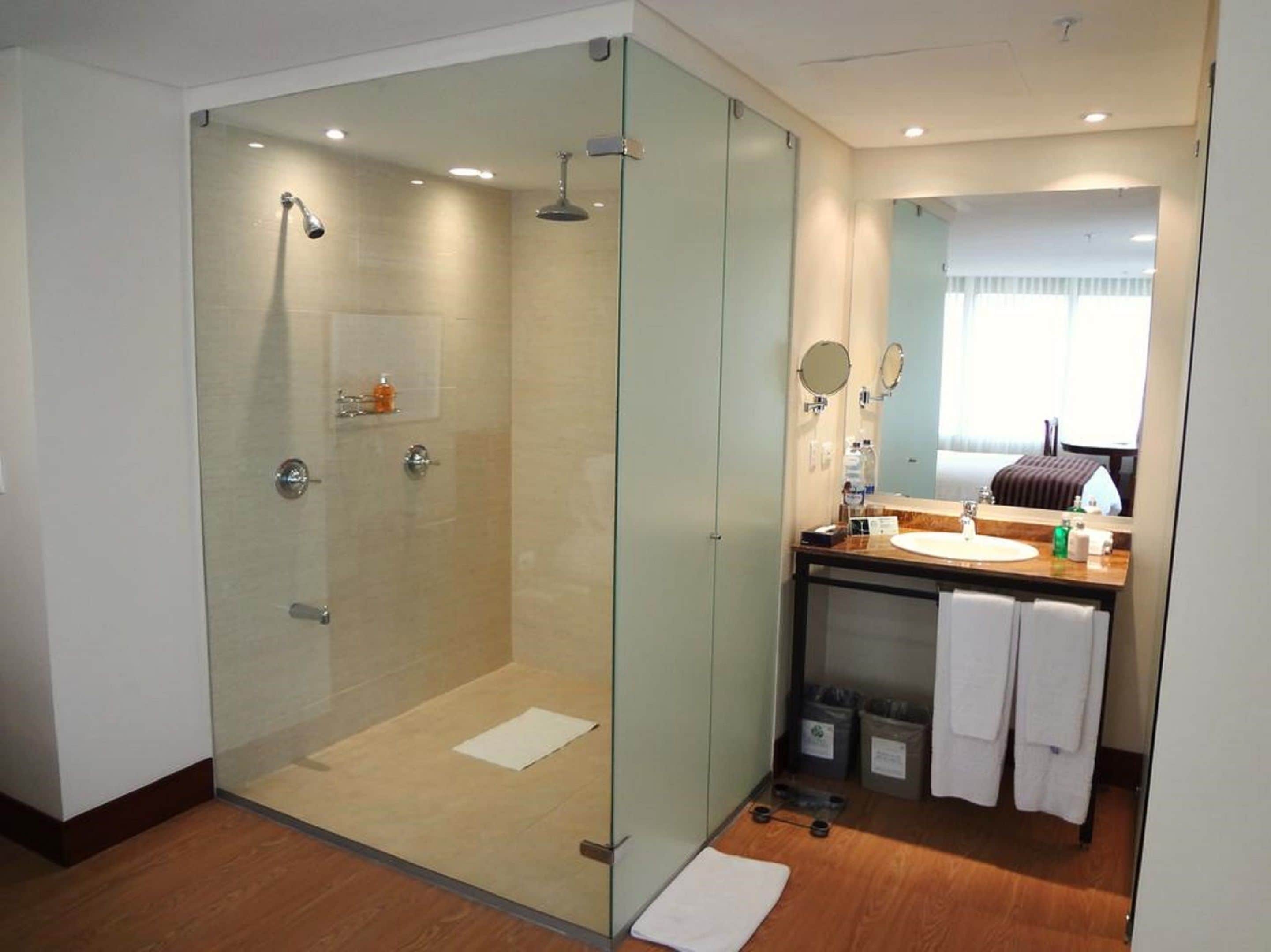 A modern bathroom with a glass-enclosed shower, a vanity with a mirror, and a window providing natural light.