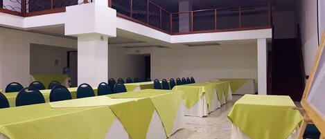 A conference room with multiple tables covered in yellow tablecloths, arranged in rows.