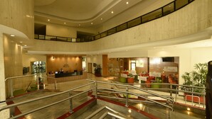 Un amplio vestíbulo con mostrador de recepción, zonas de estar y una escalera que conduce a plantas superiores.