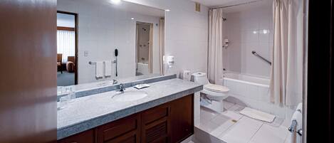 A modern bathroom with a large mirror, a sink, a toilet, and a shower area.