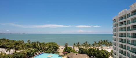 Un hotel con una piscina grande, vista a la playa y palmeras.